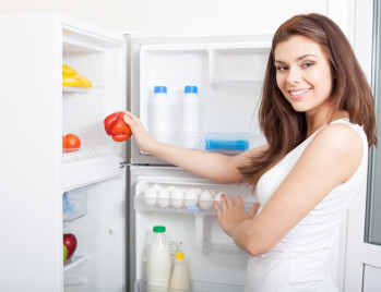 Women placing groceries in her new fridge. Link to home assistance program page.
