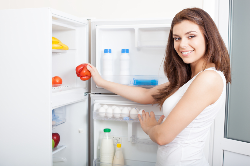 Women placing groceries in her new fridge. Link to home assistance program page.