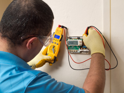 Image of man checking thermostat. Link to contractor services.