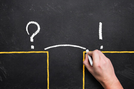 Chalkboard, two ledges, question mark on one, exclamation mark on the other, hand drawing a line bridging the gap.